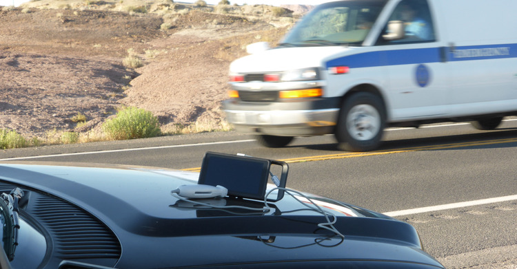 The iViz Sits on a Car as an Ambulance Zooms Past in the Background